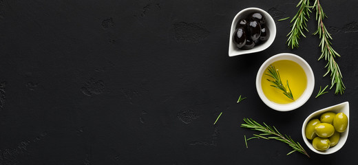 Olive oil, rosemary and olives on black.