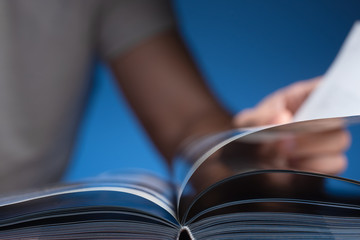 A man is flipping through a book. Focus on book binding.