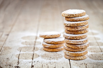 Fresh oat cookies stack with sugar powder closeup on rustic wooden table background.