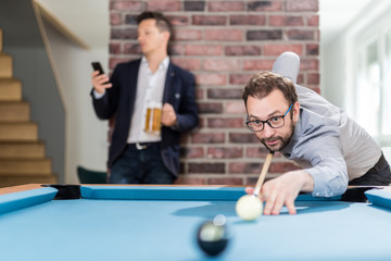 Two young businessmen playing snooker game.