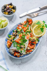 Mediterranean sea bass stuffed with tomatoes, lemons, fennel and olives - high angle view. Greek cuisine.