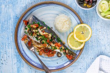 Mediterranean sea bass stuffed with tomatoes, lemons, fennel and olives - top view. Greek cuisine.