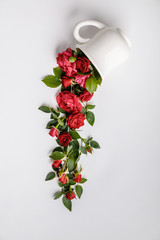 Creative layout made of coffee or tea cup with red roses on white background