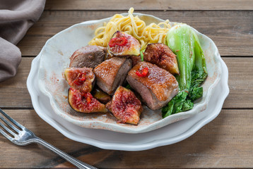 Oriental duck fillets with sticky figs, pak choi and egg noodles.