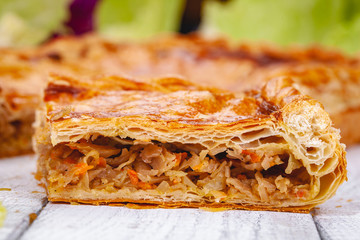 Homemade cabbage pie on wooden rustic background. Close up
