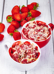 Strawberry crumble in cup on wooden rustic table. Close up