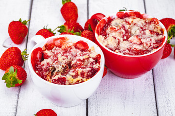 Strawberry crumble in cup on wooden rustic table. Close up