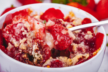 Strawberry crumble in cup on wooden rustic table. Close up
