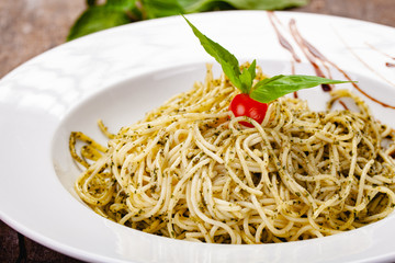 Italian pasta spaghetti with homemade pesto sauce on white plate. Close up