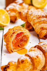Croissants with lemon jam on white wooden background. Close up