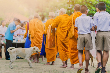Teachers and students together make merit to give food offerings to a Buddhist monk on important...