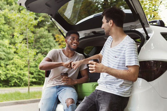Multicultural friends standing near car