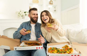 Cheerful Couple Eating Pizza In Front Of TV