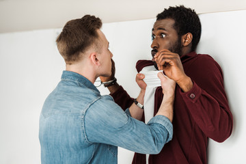 two multicultural students fighting in corridor in college
