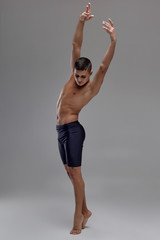 Photo of a handsome man ballet dancer, dressed in a black shorts, making a dance element against a...