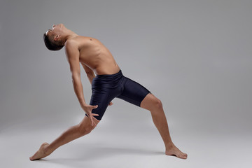 Photo of a handsome man ballet dancer, dressed in a black shorts, making a dance element against a...