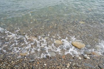 Transparent water of the Black Sea on the shore with small stones. Small stones under water. Clear water near the shore