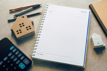 Topview blank planning note book with calculator and pen and housing model.