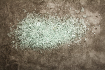 Broken glass shards on a gray background. Background of broken glass fragments. View from above.