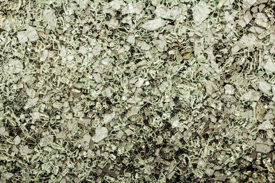 Broken glass shards on a gray background. Background of broken glass fragments. View from above.