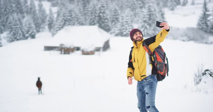 Charismatic tourist taking pictures selfies with a beautiful horse in the winter day in the middle of mountain , tourist are equipped with all travel staff