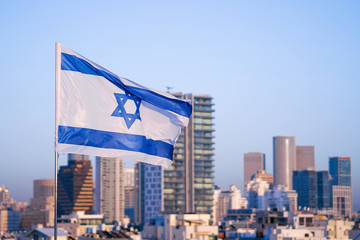 Flag of Israel on the background of modern city. Israeli flag against the background of skyscrapers...