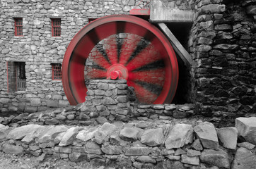 red water wheel in motion at ancient stone grist mill 