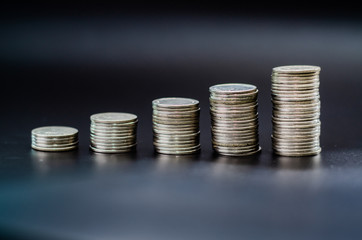 Arrange 5 coins in ascending order. On a black background.In top view.Copy space.