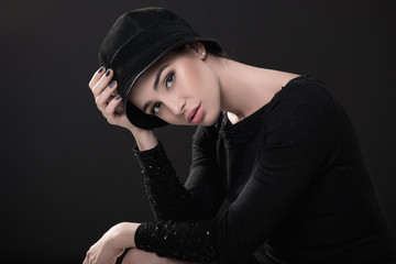 Fashion woman. Black and white portrait of beautiful young elegant lady in black dress and hat. Vintage styling. Beauty, fashion, style