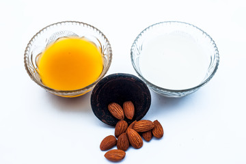 Milk face pack for natural instant glow isolated on white i.e. Raw milk well mixed with powdered almonds in a glass bowl along with entire raw ingredients.