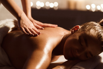 Fototapeta na wymiar Back Massage. Woman Relaxing In Atmospheric Spa Salon