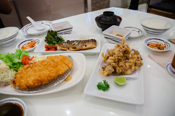 Thailand, Khon Kaen 13 April 2019: Japanese food, fried pork with bread crumbs, soy sauce, steamed squid, squid sauce, grilled squid, fried squid, salt on a white table at Fuji Japanese restaurant.