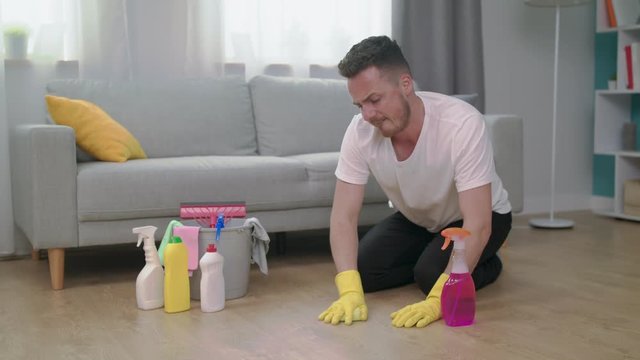 Tired angry man throws washcloth cleaning the living room