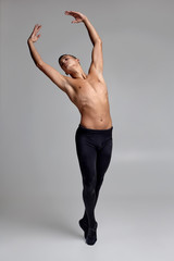 Photo of an athletic man ballet dancer, dressed in a black tights and pointe, making a dance...