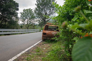 Abandoned van parked in side of hill road in a foggy bright day