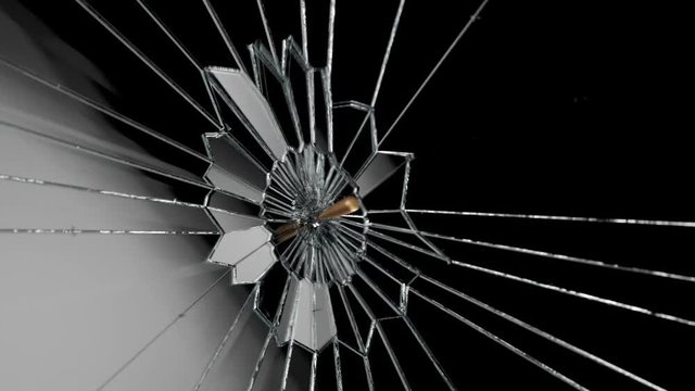 Slow-motion shot of a shiny bullet shattering a piece of transparent glass. 4KHD
