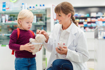 Pharmacist woman with child customer and her plush toy