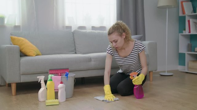 A tired woman massages her shoulder while cleaning the living room