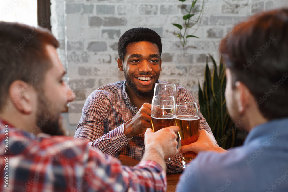 Wall mural happy guys clinking beer glasses in bar