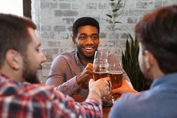 Happy Guys Clinking Beer Glasses In Bar