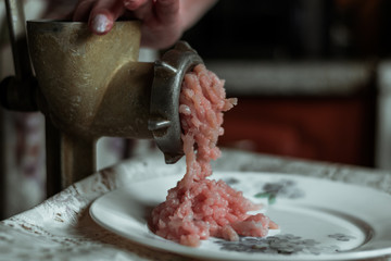 Woman making mince meat grinder on vintage iron. The process of grinding meat