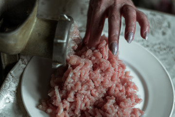 Woman making mince meat grinder on vintage iron. The process of grinding meat