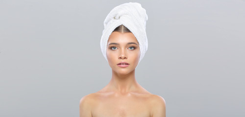 Beautiful young woman with perfect skin with a towel on her head, isolated on a gray background. - 267826230