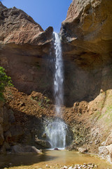 Fototapeta na wymiar Small waterfall splashing down in a small pool in a rocky landcape