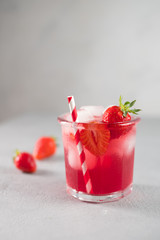 Srawberry soda drink with ice on grey background.