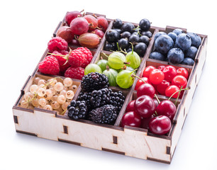 Colorful berries in wooden box on white background. Top view.