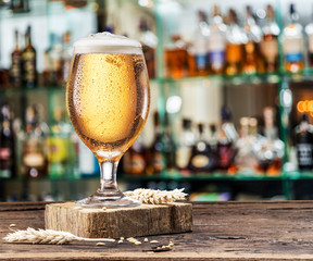 Chilled glass of light beer on the bar counter. Blurred bar background.