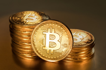 Shiny physical bitcoins on golden background. Blockchain technology.