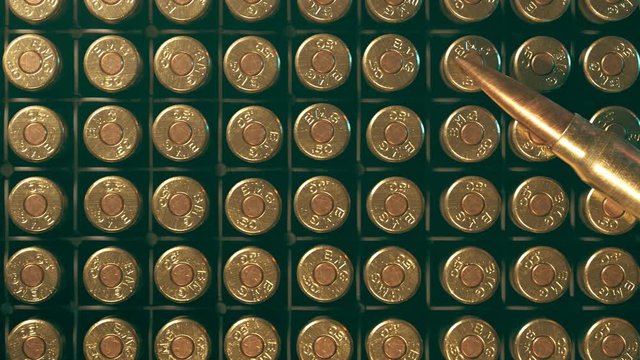 Rows of .50 BMG machine gun ammunition in plastic container.  One bullet on top.
