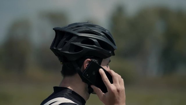 Cyclist Talking On Phone.Athlete Talking On Mobile Phone.Cyclist Using Mobile Phone.Man With Bicycle Talks On The Phone.Young Man Athlete Talking On Phone Near Field.Athlete Answer The Phone Call.